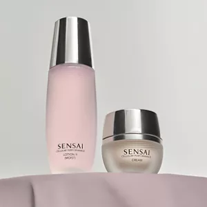 Flacon de Cellular Performance Lotion 2 (Hydratante) au côté d’un pot de crème sur une table mauve